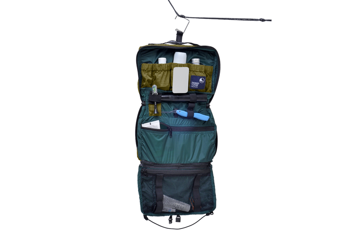 Wash Bag in army green, opened and hung from a line, pockets filled with toiletries, mirror and toothbrush