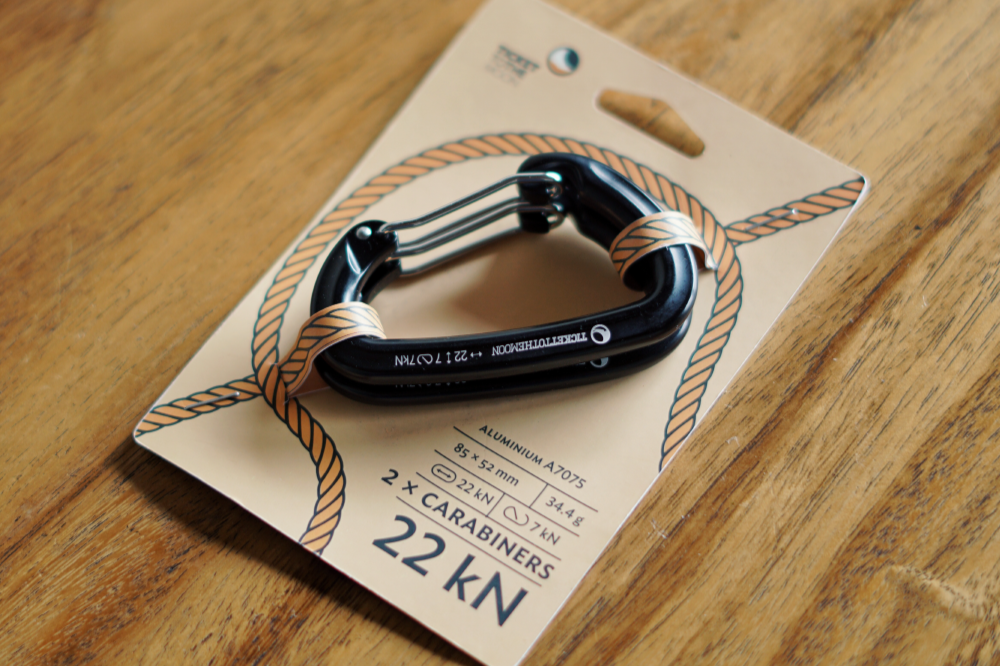 Carabiner 22kN (2-Pack) in its card packaging on a wooden table. 2 x carabiners 22 kN, aluminium A7075, 85 x 52 mm, 34.4 g, 7 kN gate open