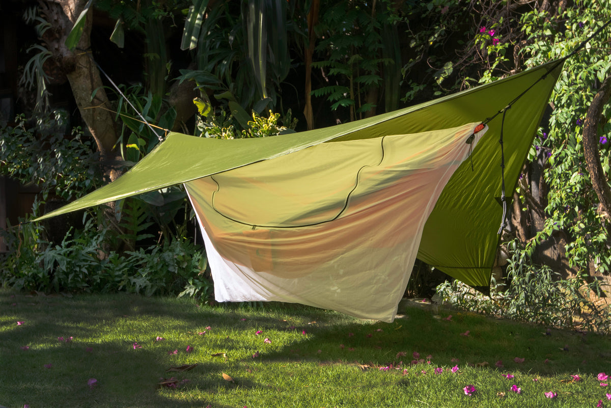 Universal Bug Net 360° hanging under a green tarp in a sunny garden, shown without a hammock inside