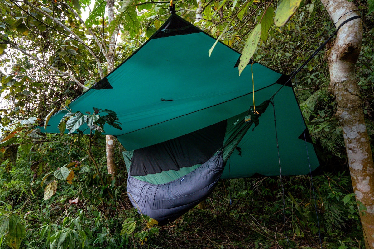 FULLMOON TARP in teal pitched over a hammock with a grey underquilt in dense jungle