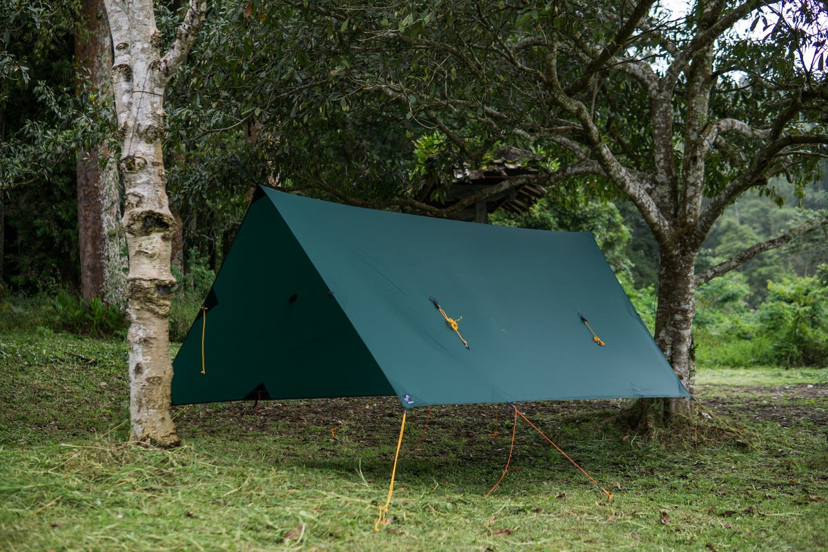 FULLMOON TARP in dark green pitched as an A-frame shelter on grass with yellow and orange guylines