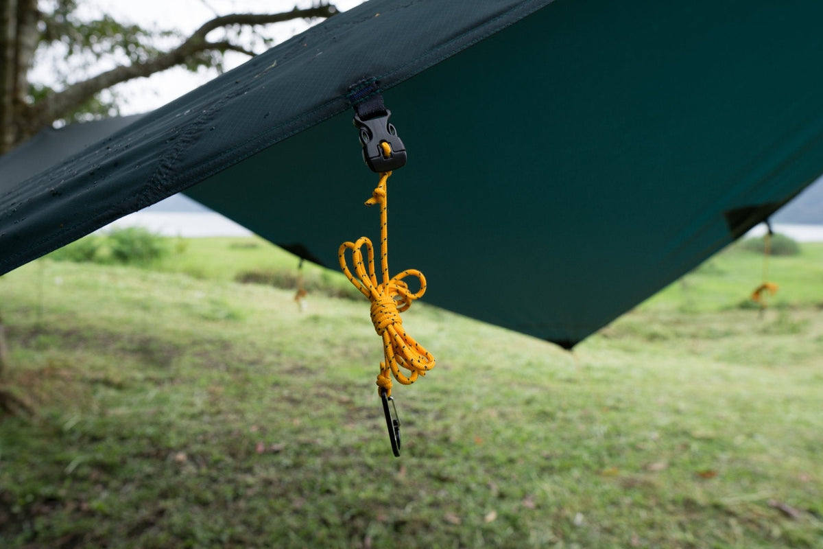 Close-up of a Moon Tarp corner buckle with a coiled yellow guyline