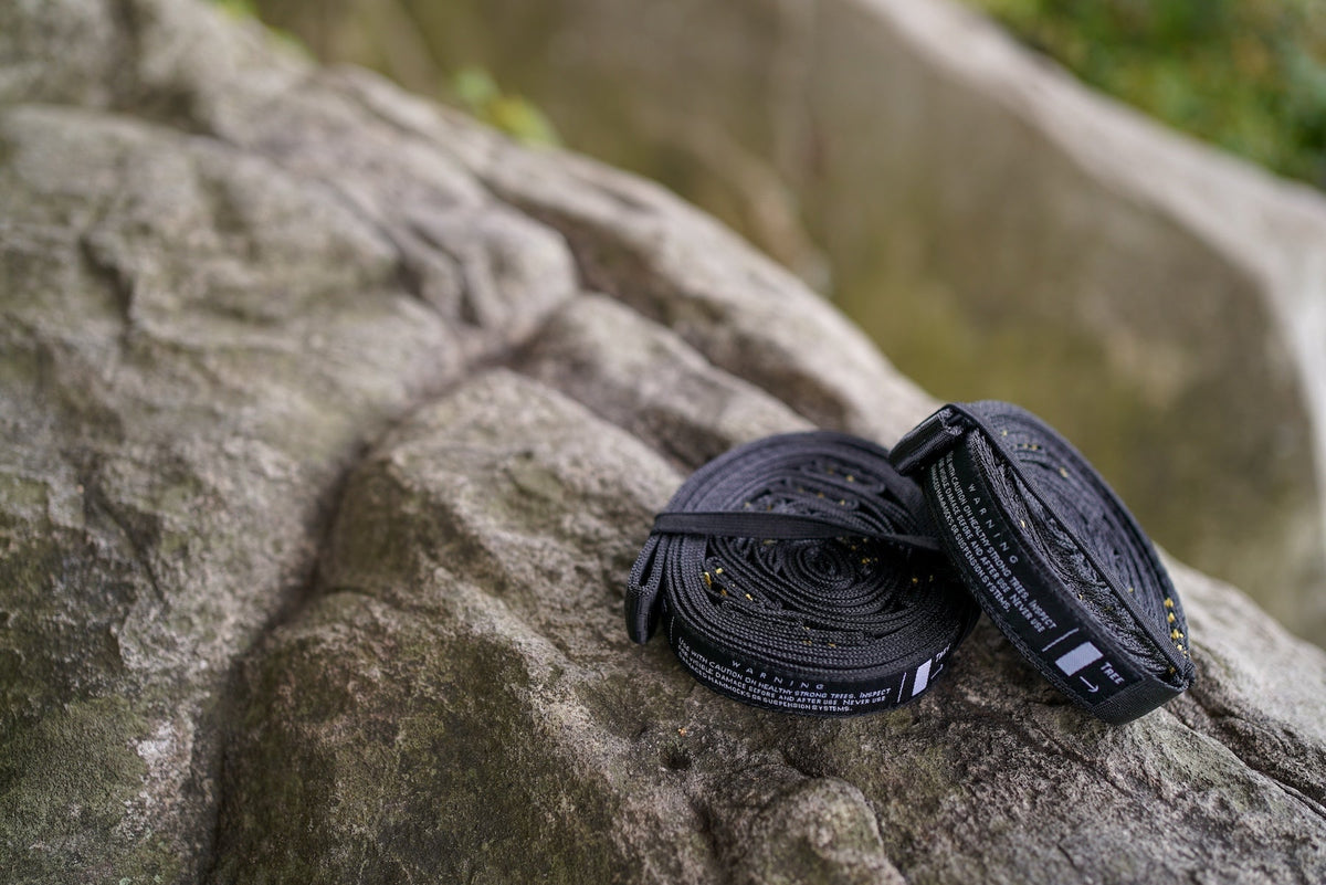 Moon Straps (2-Pack) in black, two rolled straps resting on a mossy rock