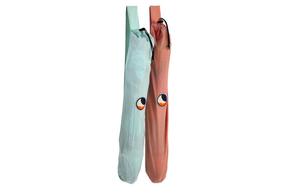 Mini Moon Chair in mint and in coral, packed in drawstring carry bags with shoulder straps