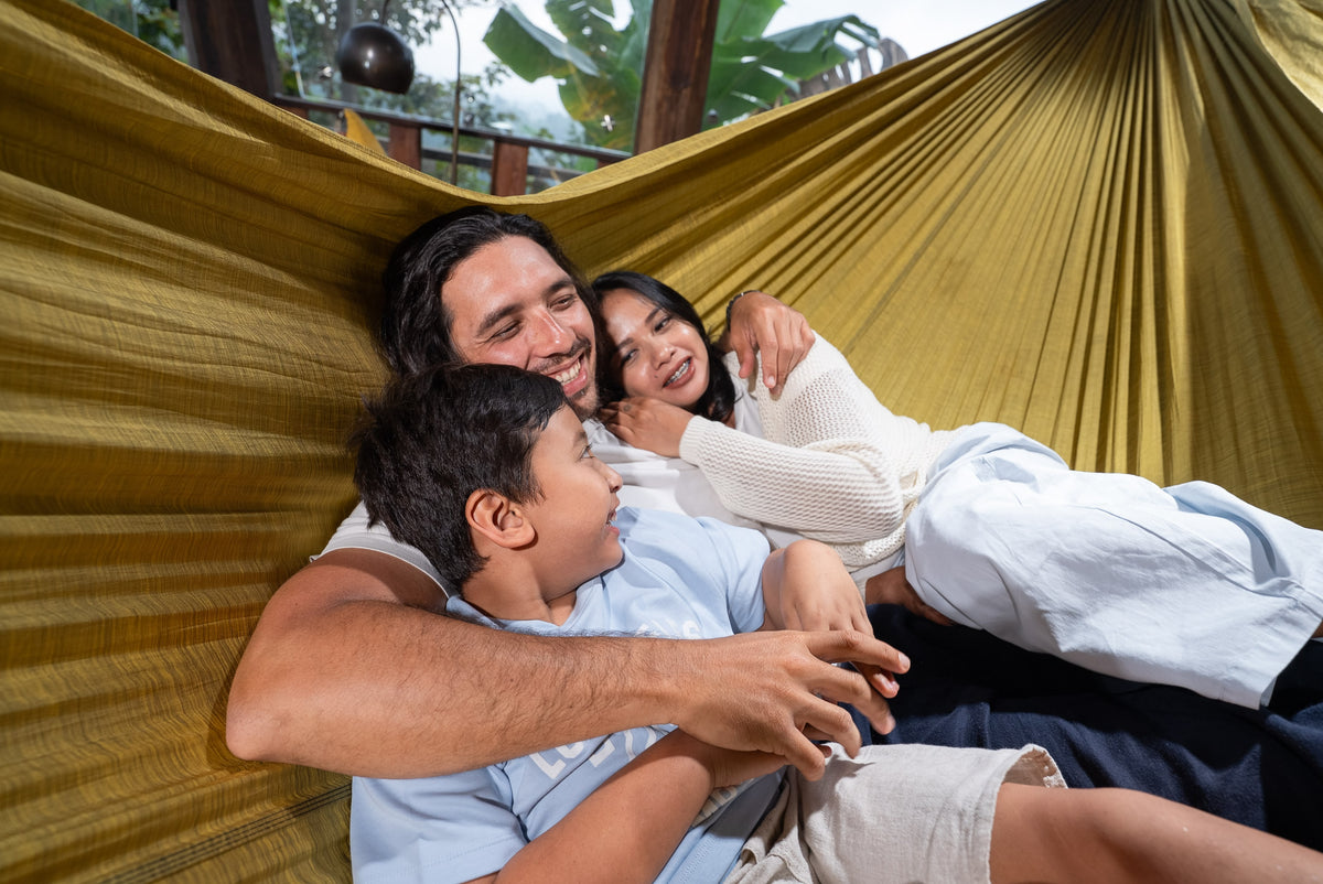 Father, mother and son cuddling and laughing together in a golden Home Hammock 520
