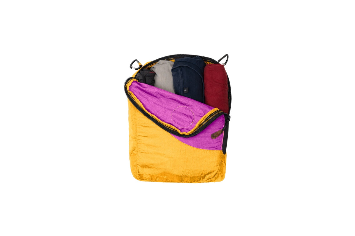 Travel Cube Medium in yellow and magenta, unzipped and packed with rolled clothes