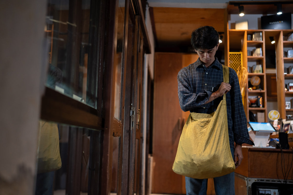 Man in a checked shirt carrying a Sparkling Gold Moon Bag Large (Premium) over his shoulder in a shop