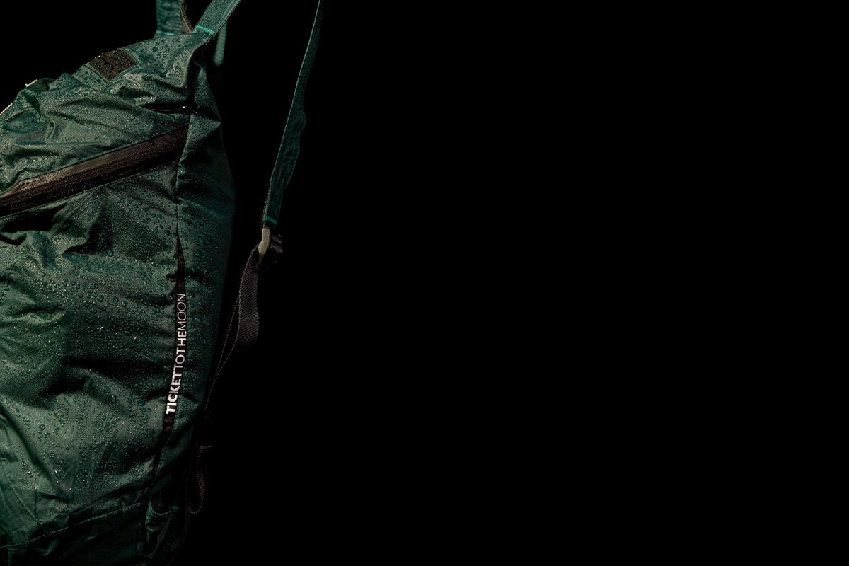 Close-up of a green water-resistant backpack with raindrops beading on the fabric