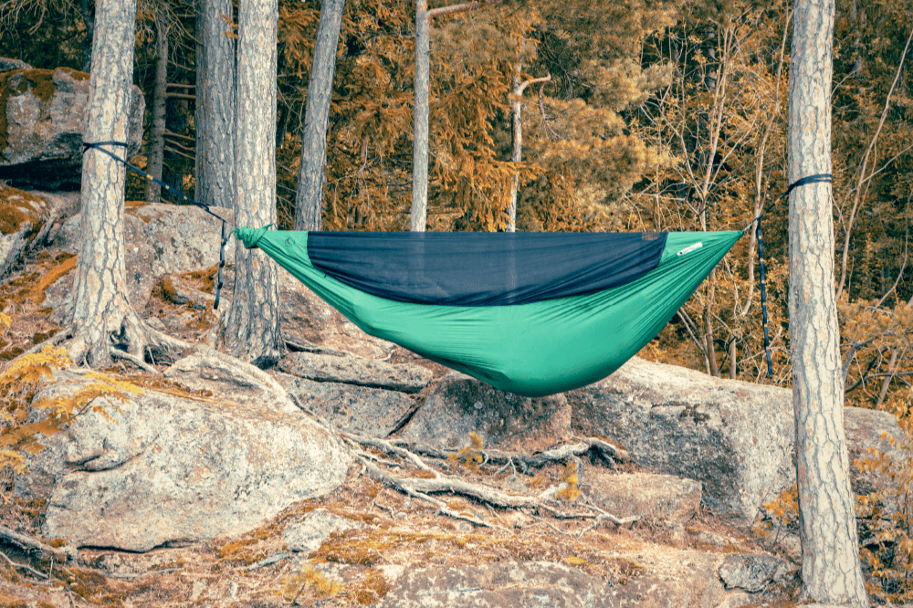 Green Pro Hammock (Custom) with black bug net hung between pine trees over granite rocks