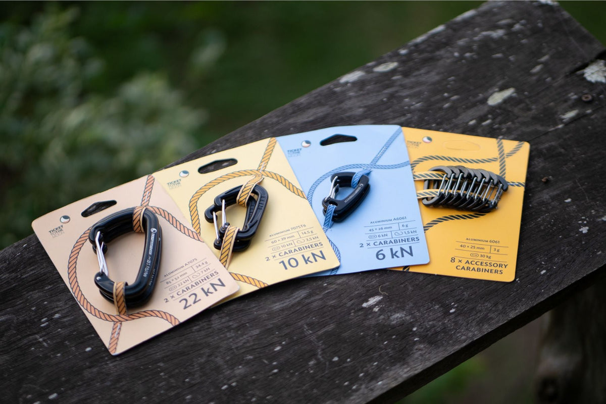 Lightest Carabiner 6kN (2-Pack) card next to other carabiner packs (22 kN, 10 kN, 6 kN, 8 accessory carabiners) on a wooden rail